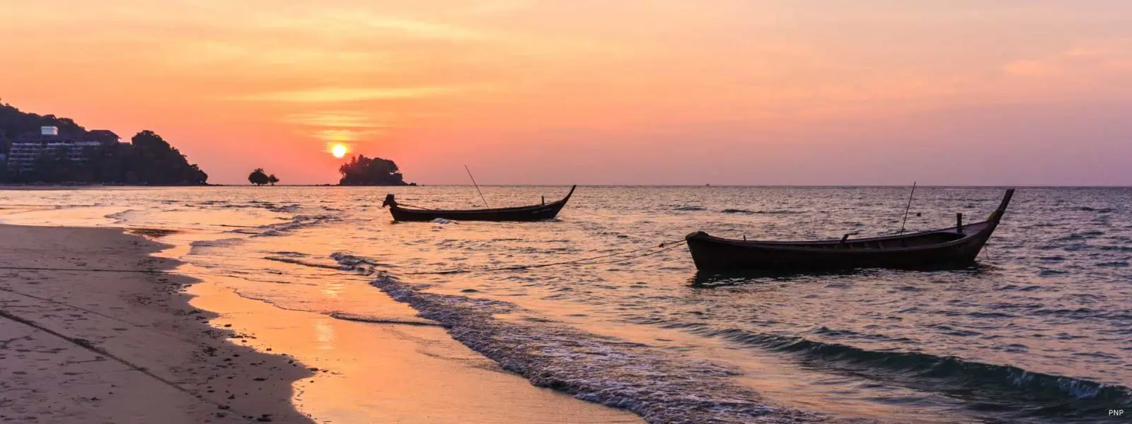 Sunset over Nai Yang Beach with longtail boats